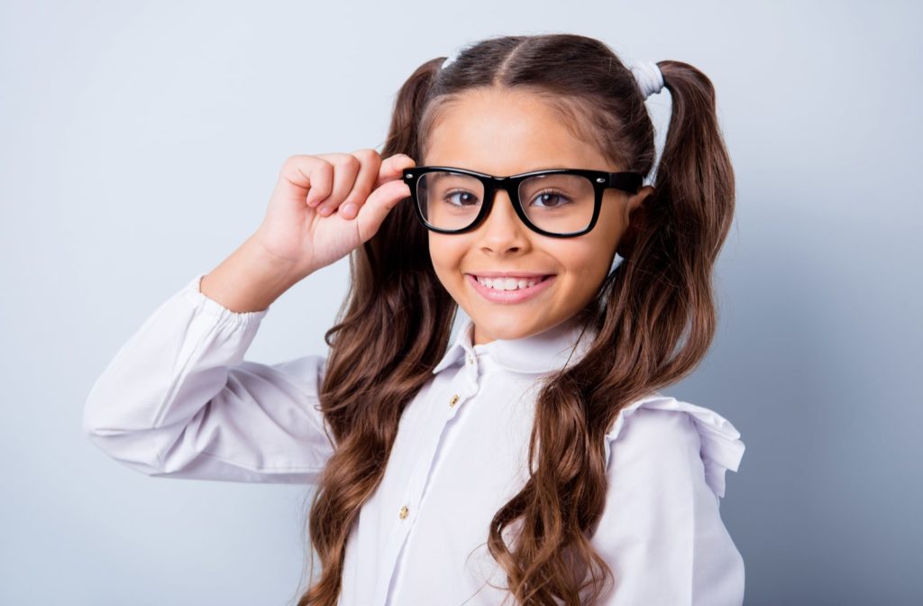 A young girl wearing glasses and smiling at the camera