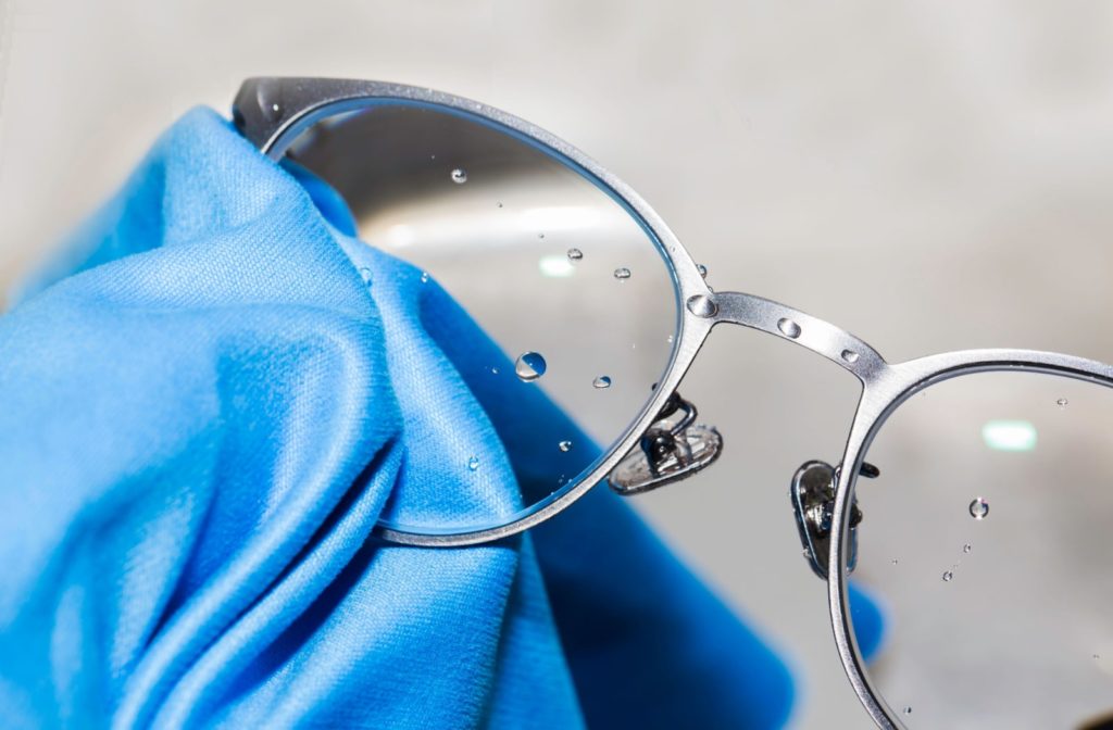 Someone uses a blue micro-fiber cloth to clean their glasses